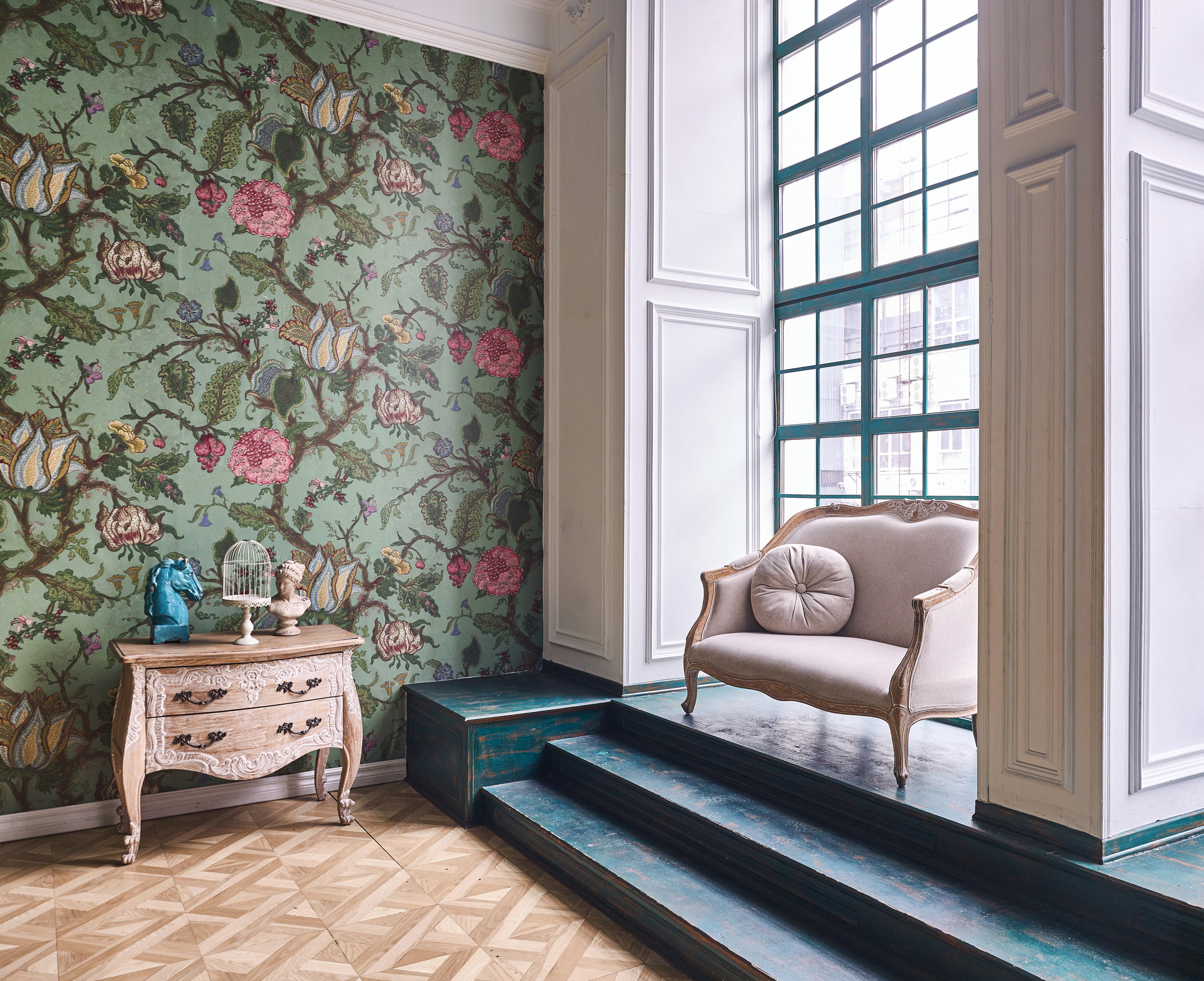 An elegant room with floral wallpaper a classic armchair and a small table beside a large window
