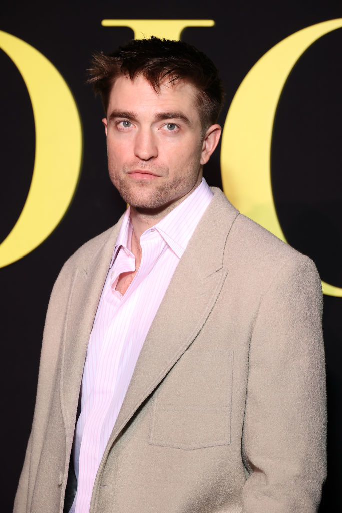 Robert in a textured suit and unbuttoned pink shirt at a media event