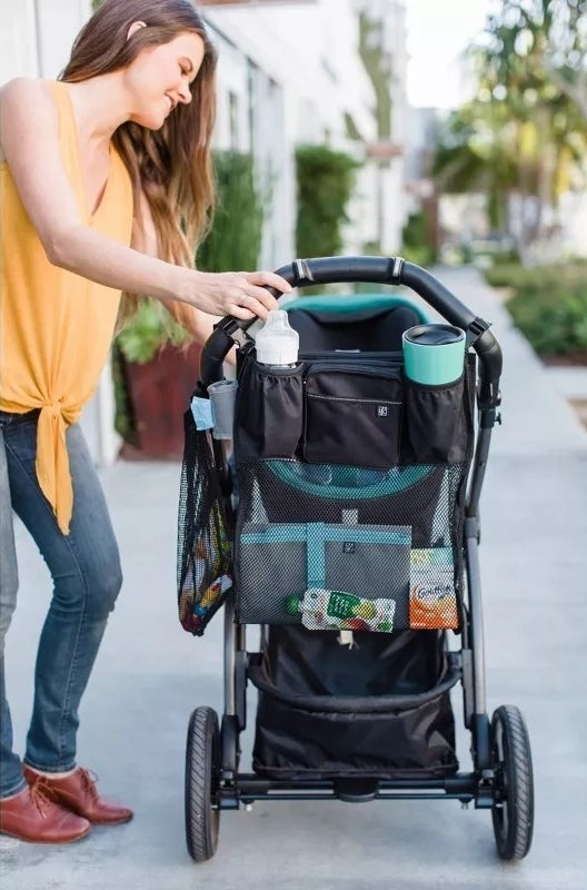 Person using a stroller organizer with various compartments while outdoors