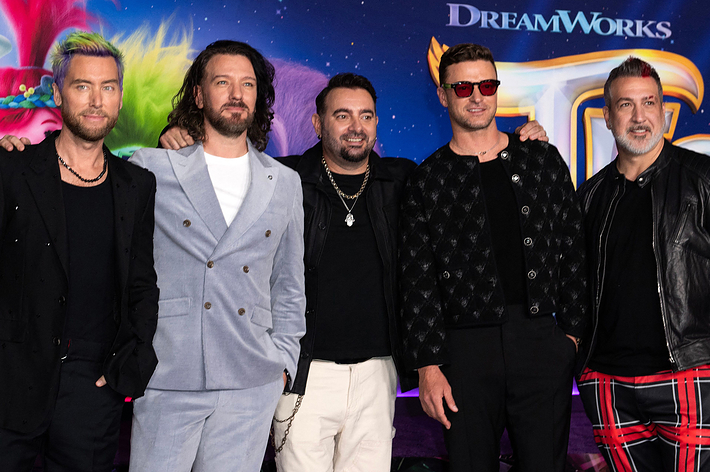 Five members of the NSYNC pose together at a DreamWorks event. They are dressed in various trendy outfits