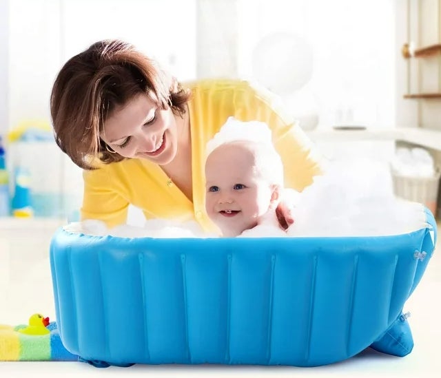 woman model cleaning baby model in portable inflatable tub