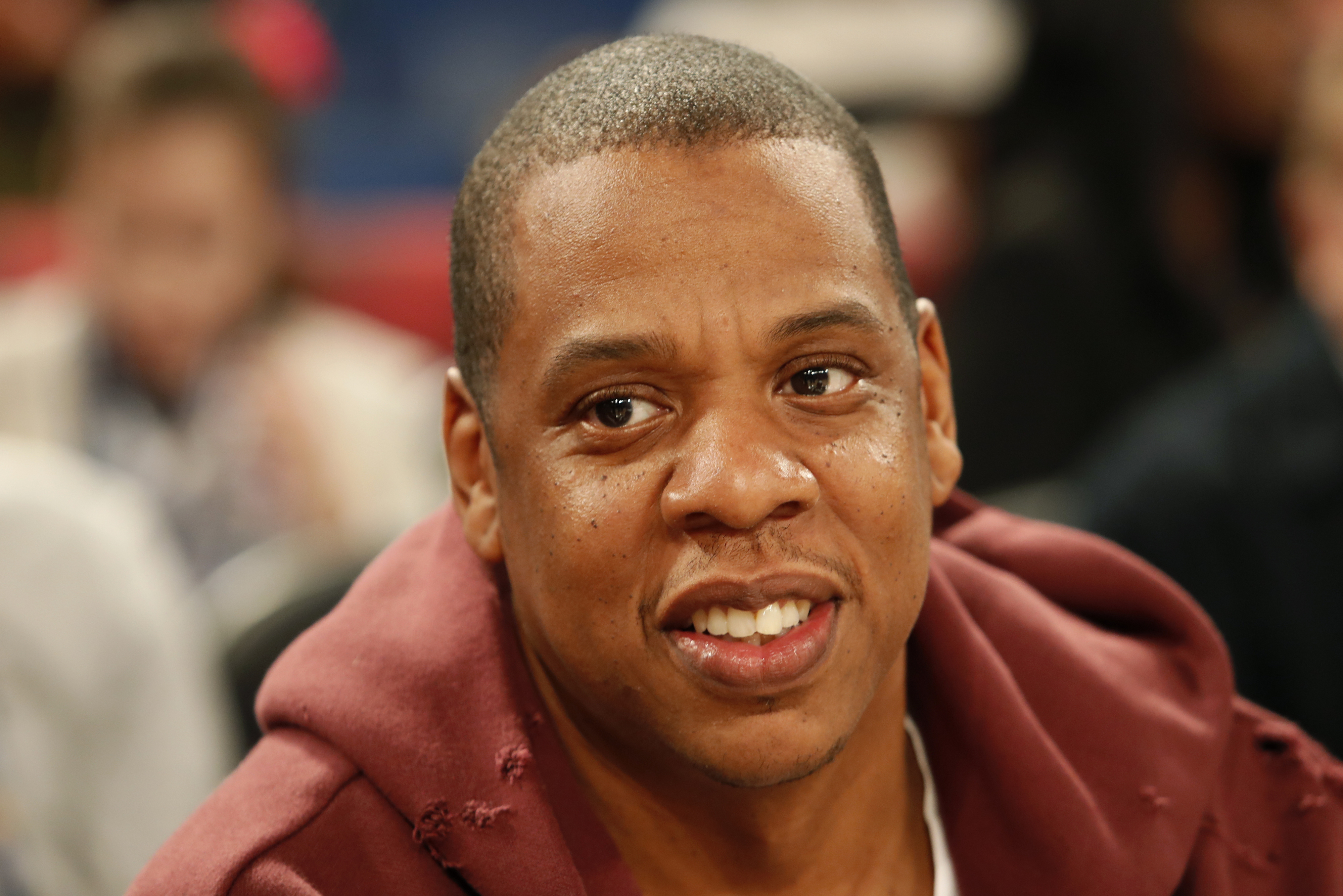 Close-up of Jay-Z in a hooded sweatshirt, smiling at an event