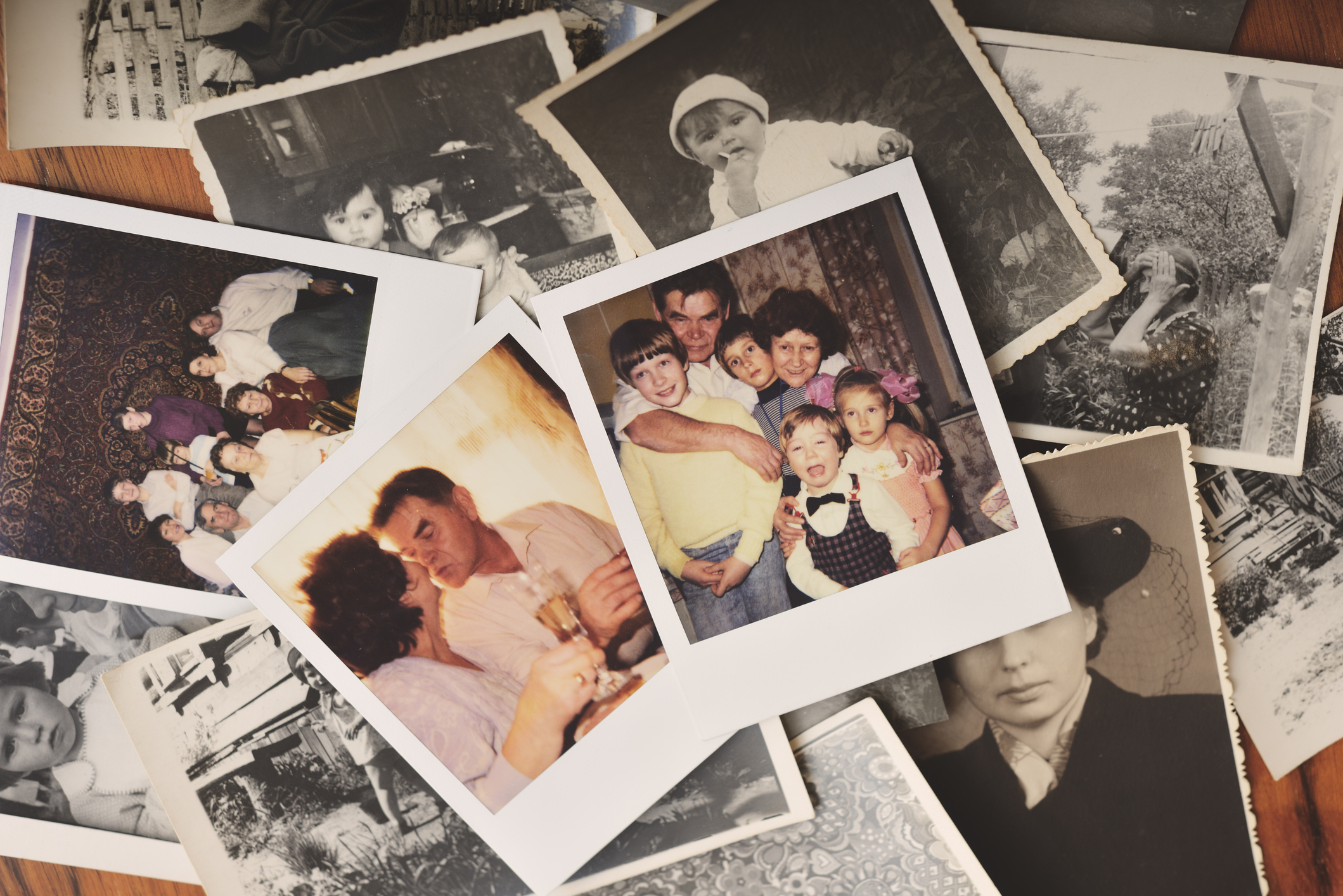 Assorted old photographs spread out, showcasing various stages of family life and relationships