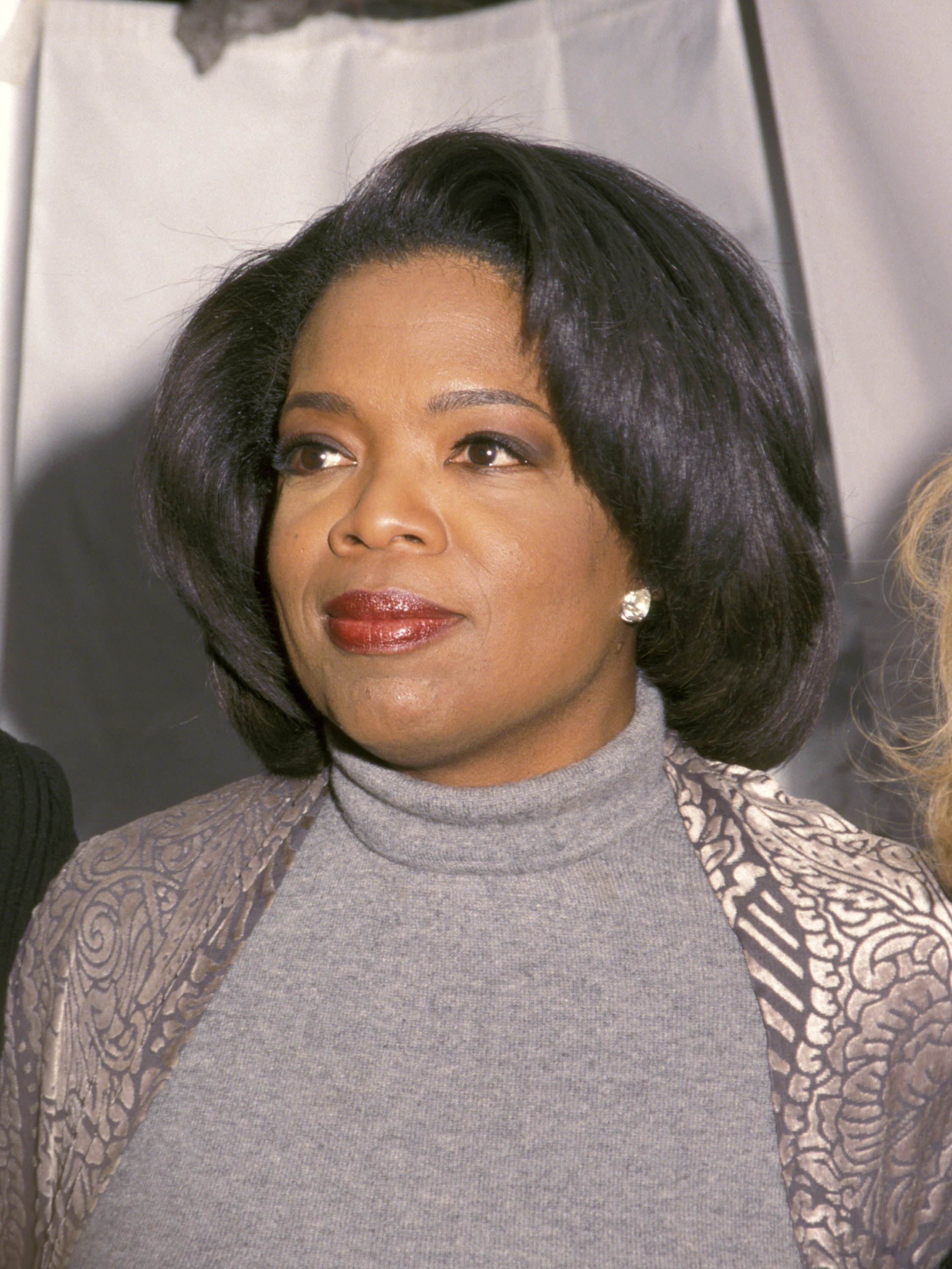 Oprah Winfrey in a turtleneck and lace jacket at an event