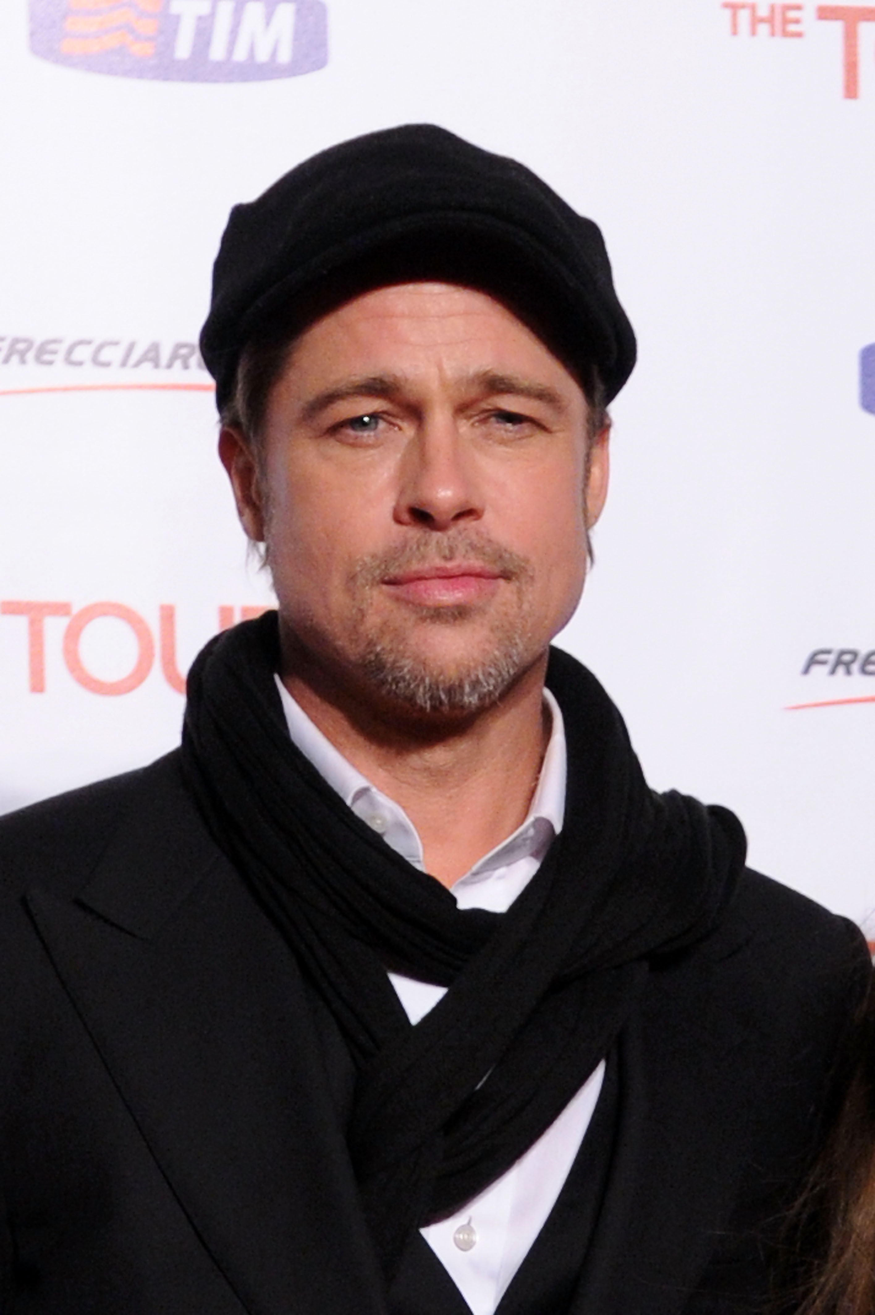 Brad in black hat and scarf with a casual suit at a media event