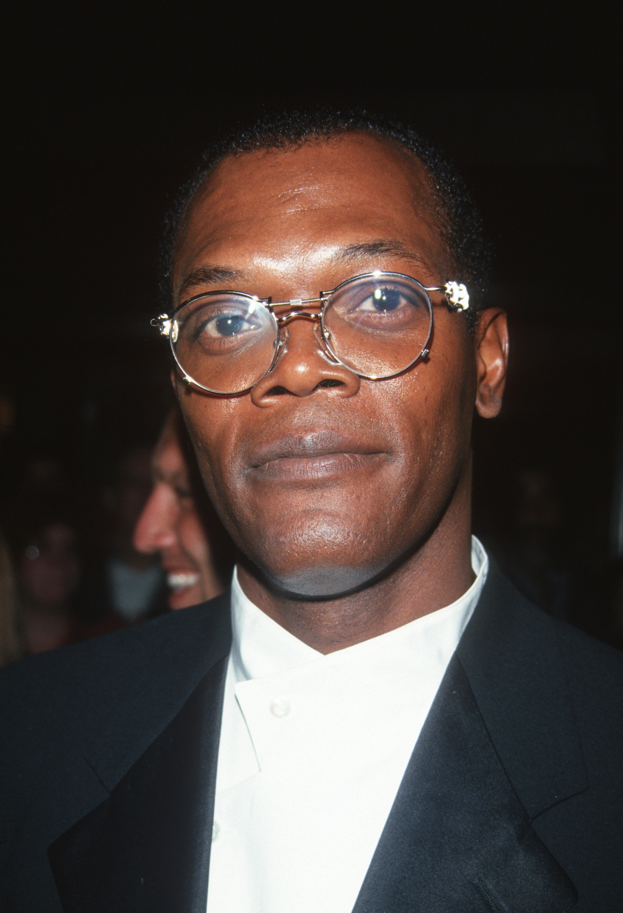 Samuel L. Jackson wearing glasses and a classic black suit with a white shirt
