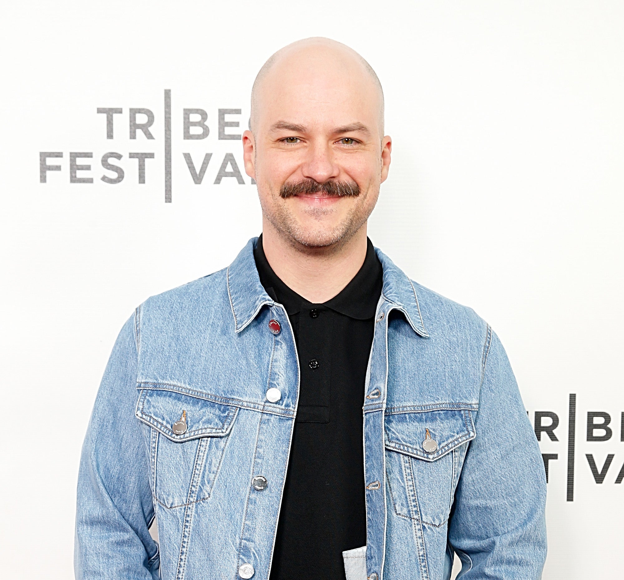 Man smiling in a black shirt with a denim jacket at Tribeca Film Festival