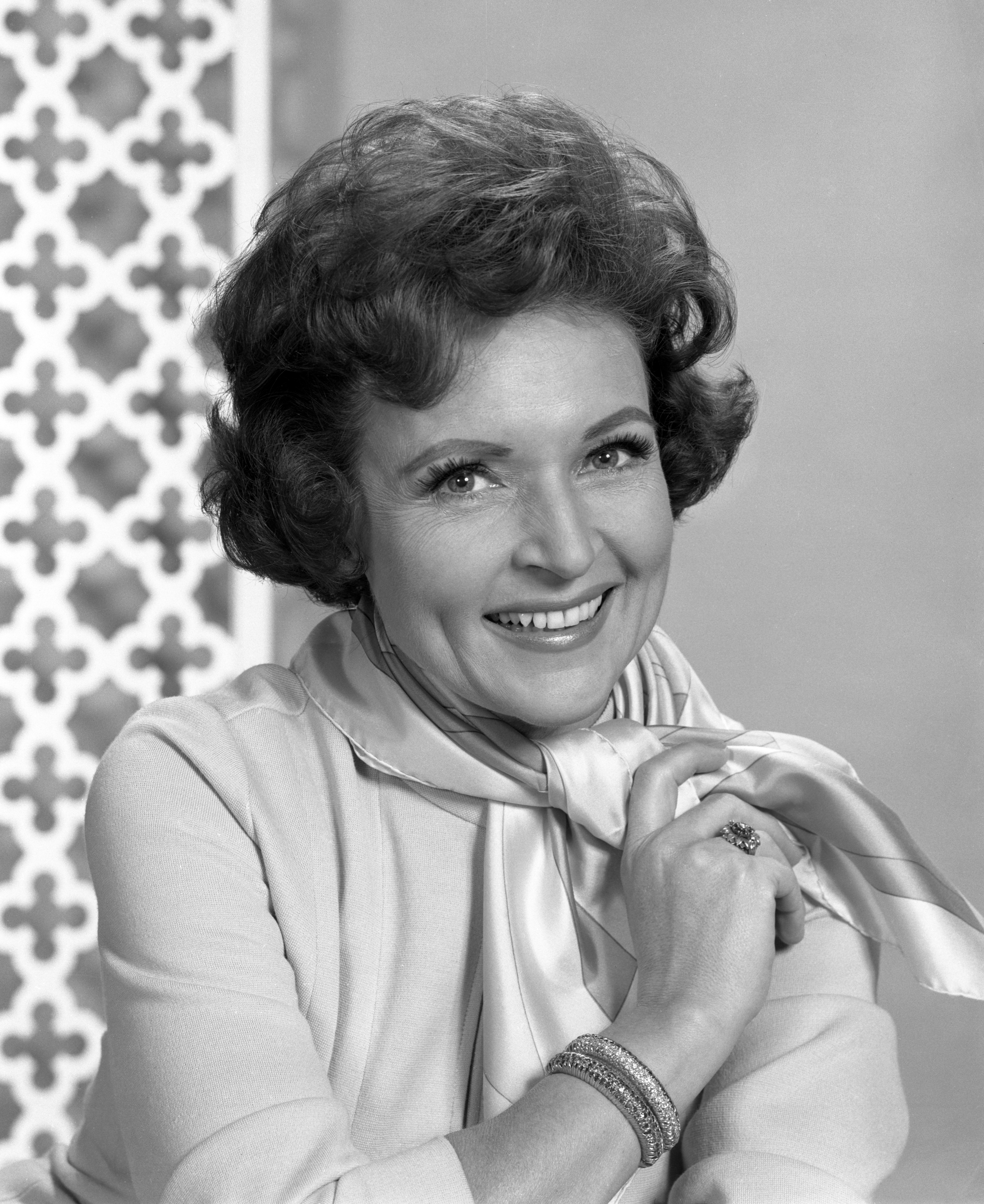 Betty White smiles, wearing a light scarf and a bracelet