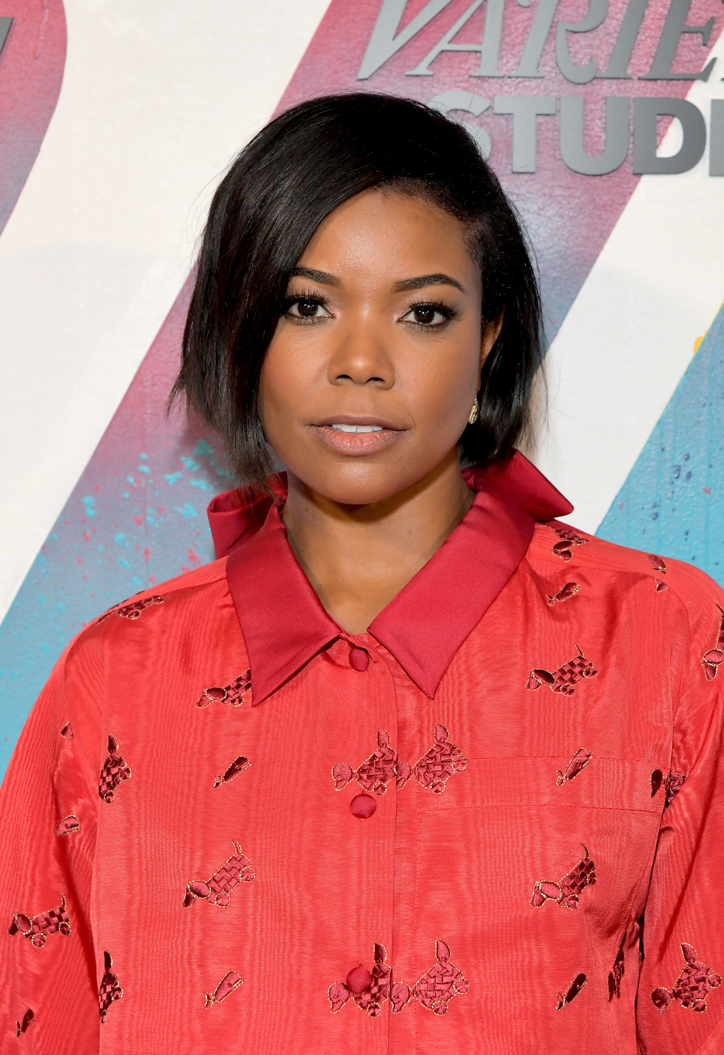 Gabrielle Union poses in a red shirt with floral embroidery at an event