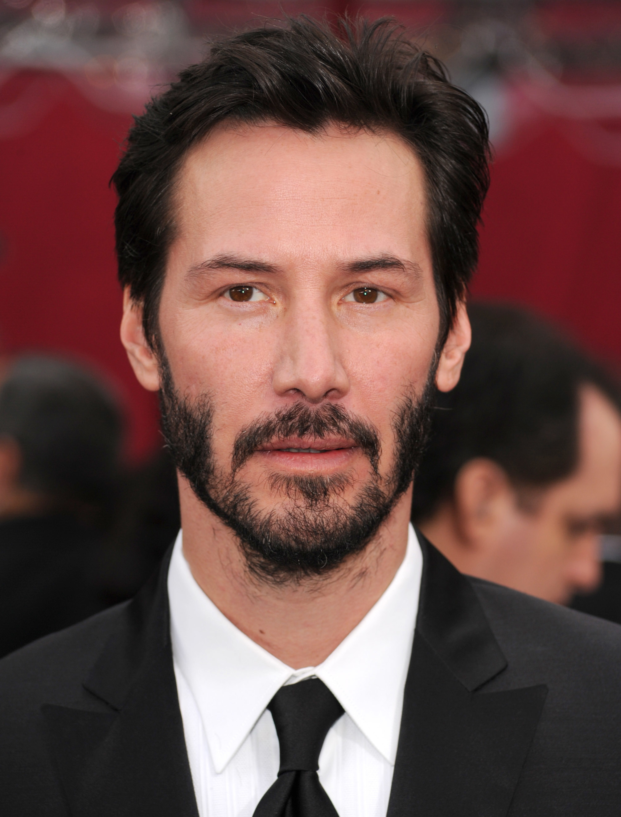 Keanu in a black suit and tie on a red carpet