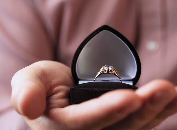 Person holding an open ring box with an engagement ring, symbolizing a marriage proposal