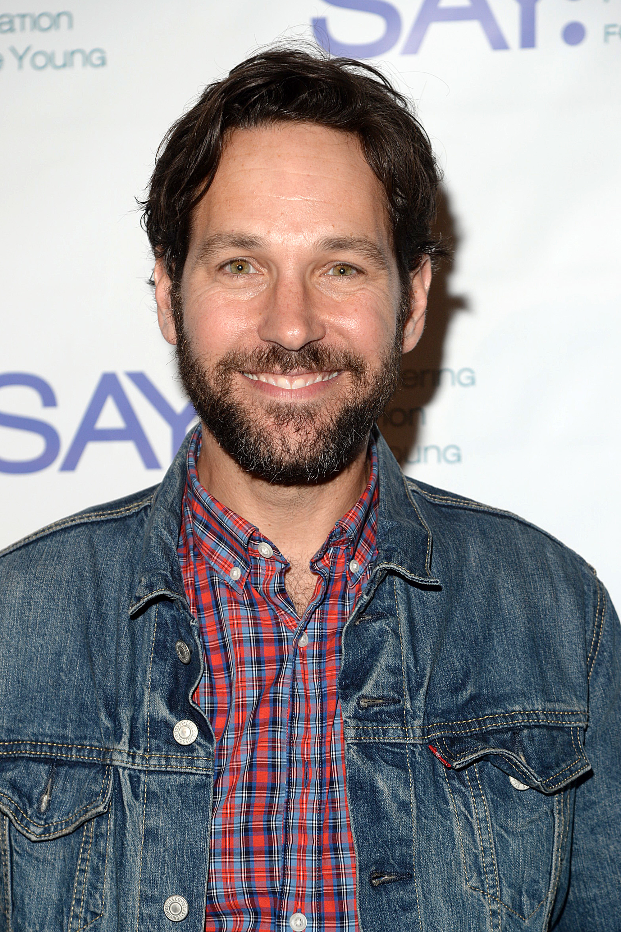 Paul smiling in a denim jacket over a plaid shirt at an event