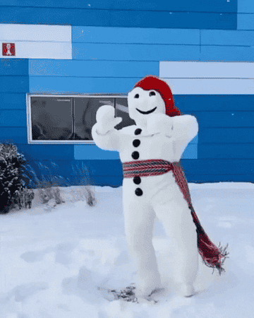 Large snow sculpture of a figure with a red hat and long scarf giving a thumbs up