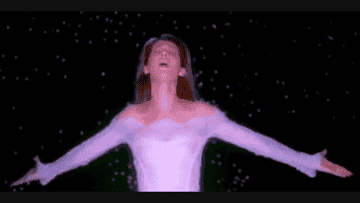 Celine Dion in a white dress with long sleeves, performing with arms outstretched