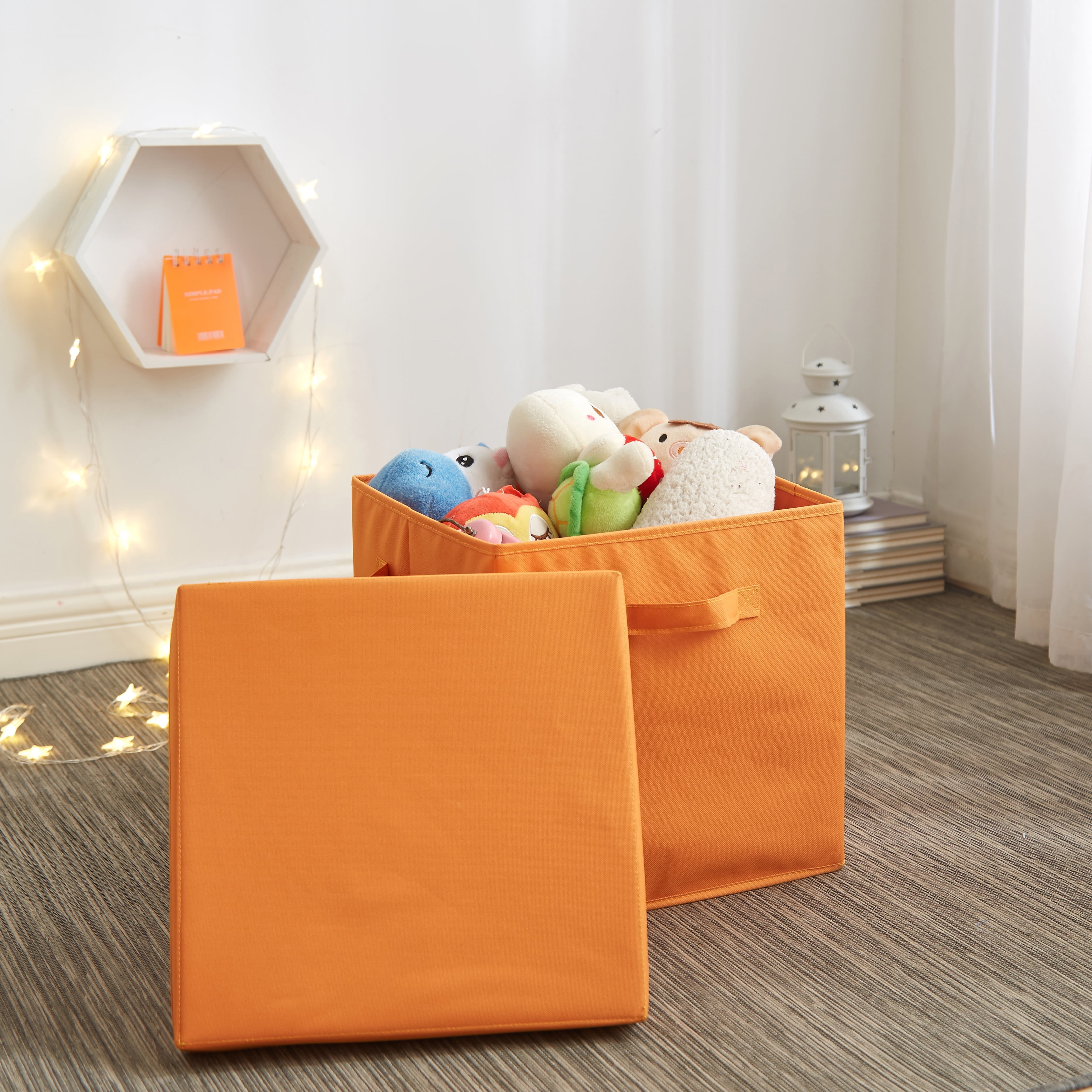 Two orange storage boxes on a floor, one open with stuffed toys inside