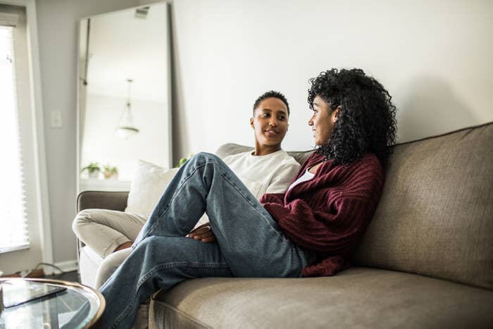 Two people conversing while sitting on a couch, one with legs crossed