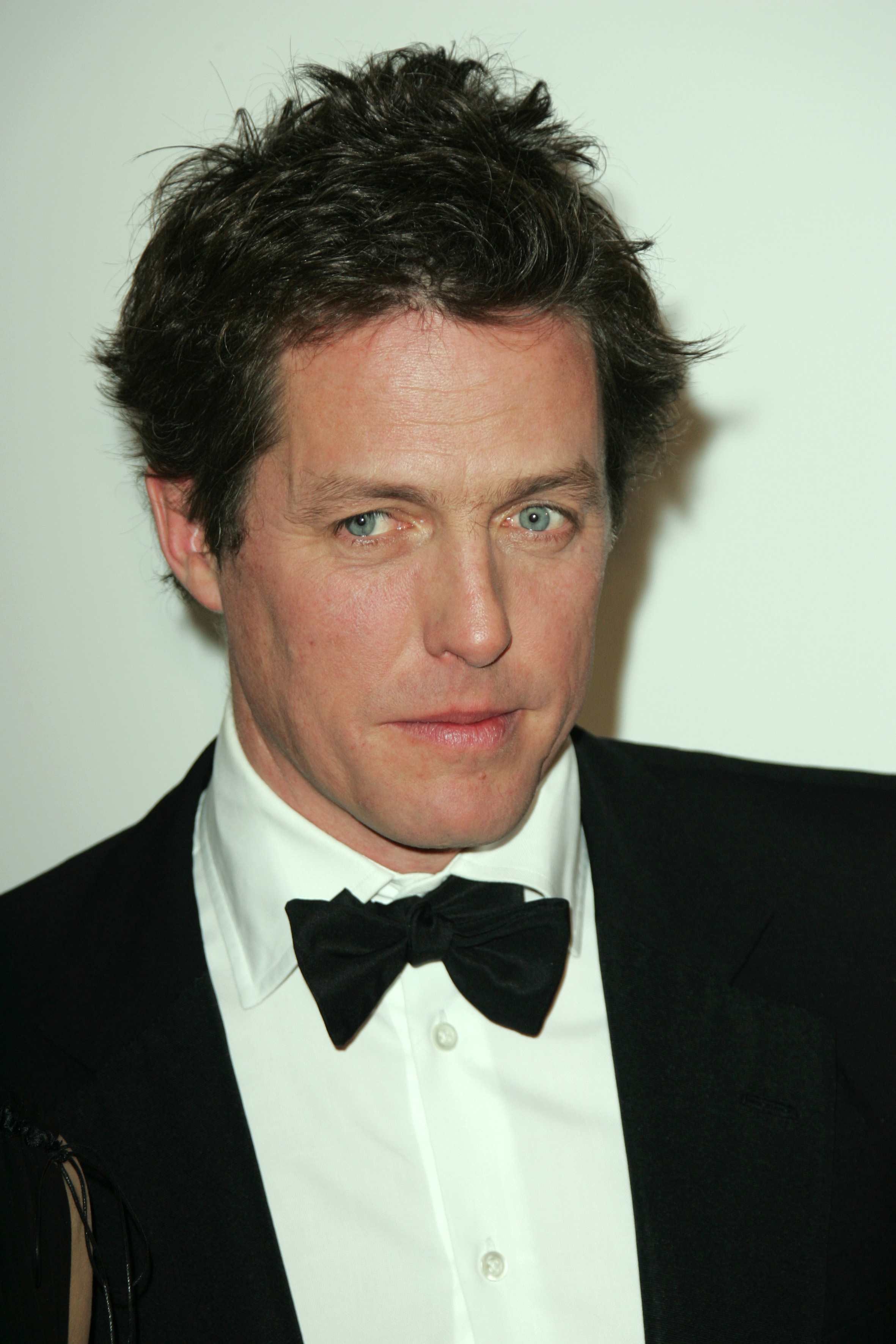 Hugh Grant in a classic tuxedo with a bow tie at a formal event