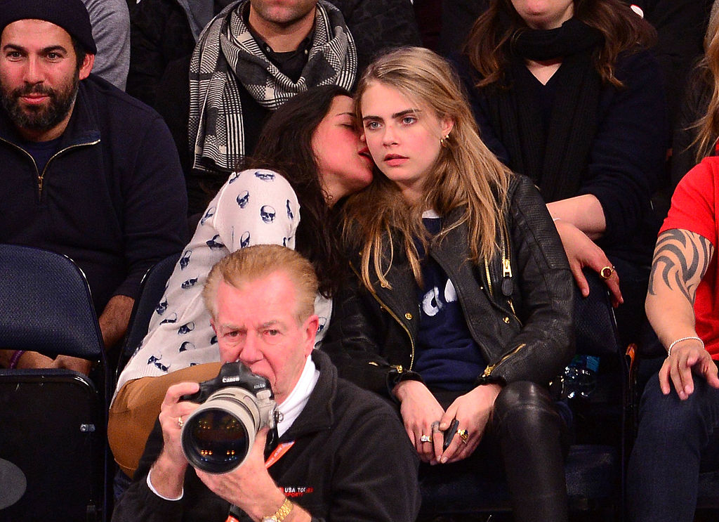 Michelle sitting courtside, whispering to Cara, photographer in foreground