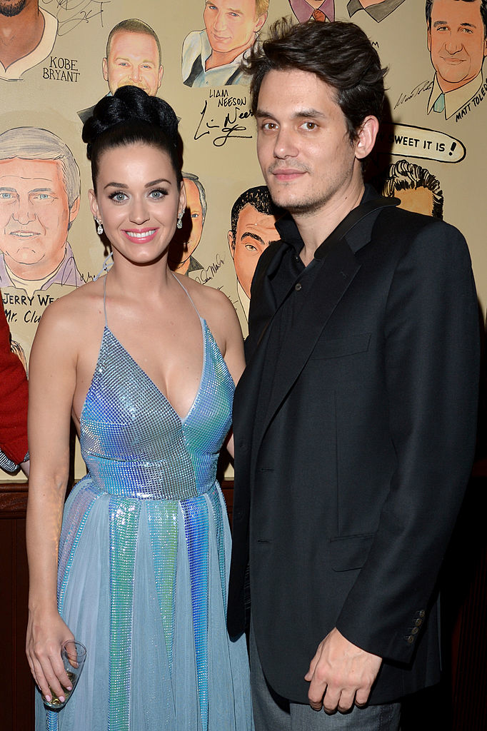 Katy smiling and wearing a shimmering sleeveless dress, John in a black suit without a tie
