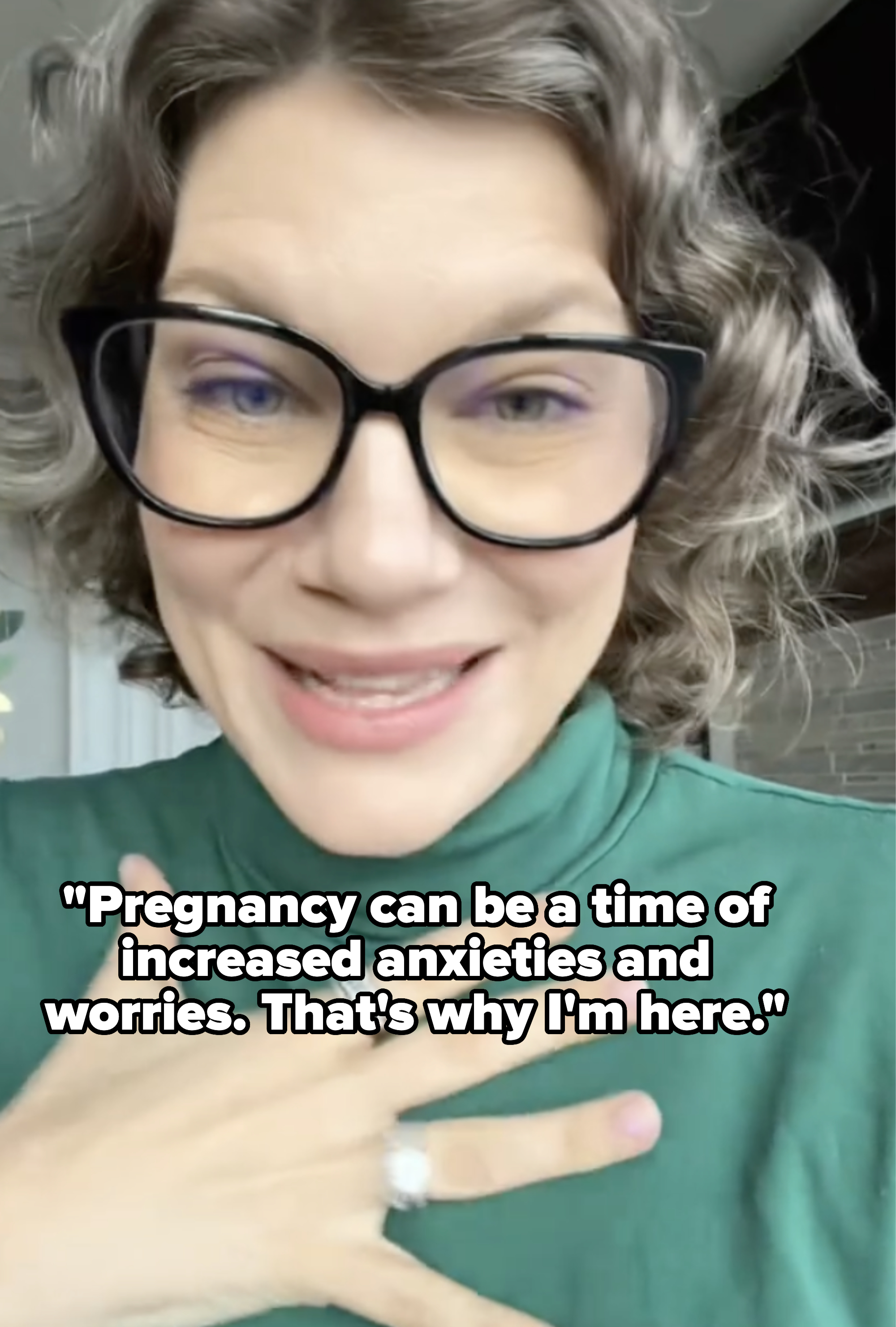 Woman with glasses smiling, wearing a green top, with caption: &quot;Pregnancy can be a time of increased anxieties and worries; that&#x27;s why I&#x27;m here&quot;