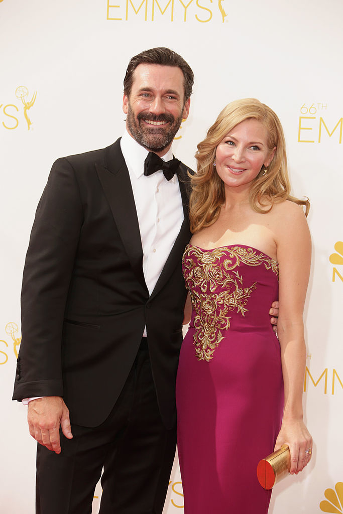 Jon smiling in a black tuxedo and Jennifer in a strapless pink gown with gold embroidery at the Emmys