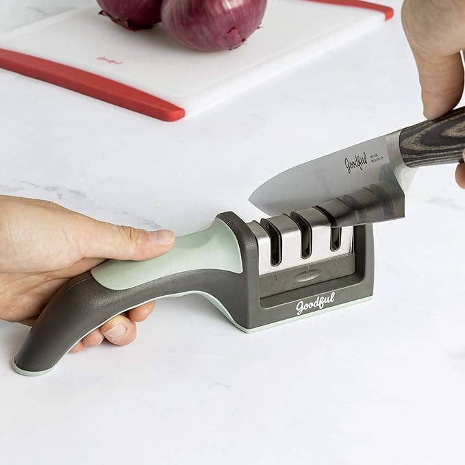 Hand using the knife sharpener on a kitchen countertop