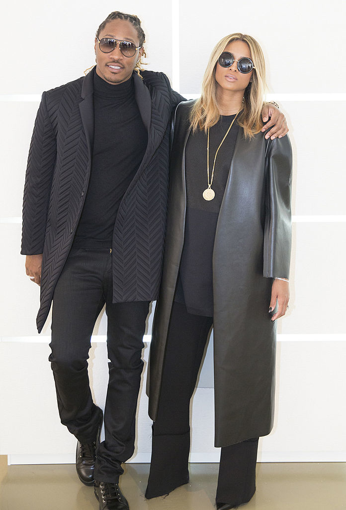 Future in a textured coat and turtleneck with his arm around Ciara in a long coat , both wearing sunglasses