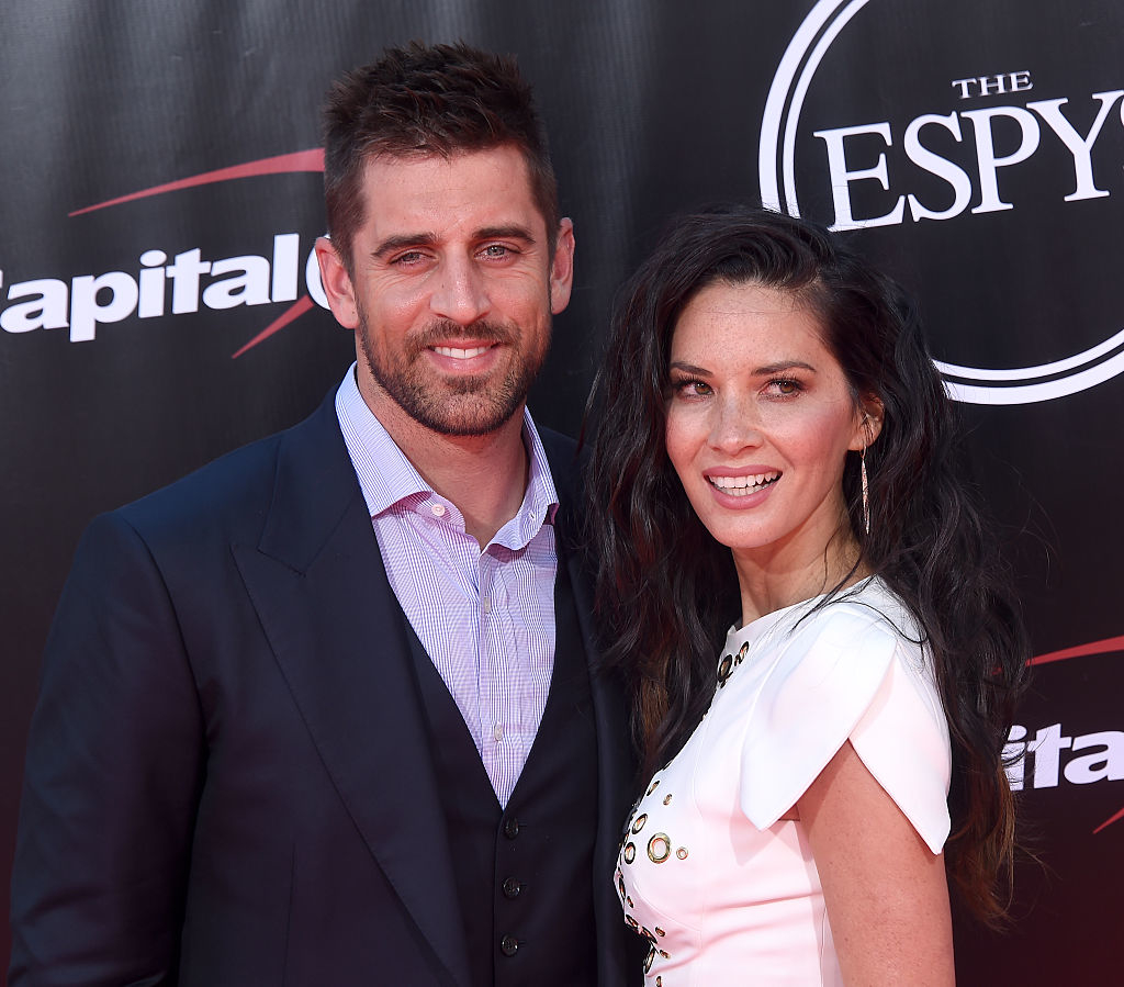 Aaron and Olivia posing at the ESPYs, he in a navy suit with a pink shirt, and she in a white dress with gold details