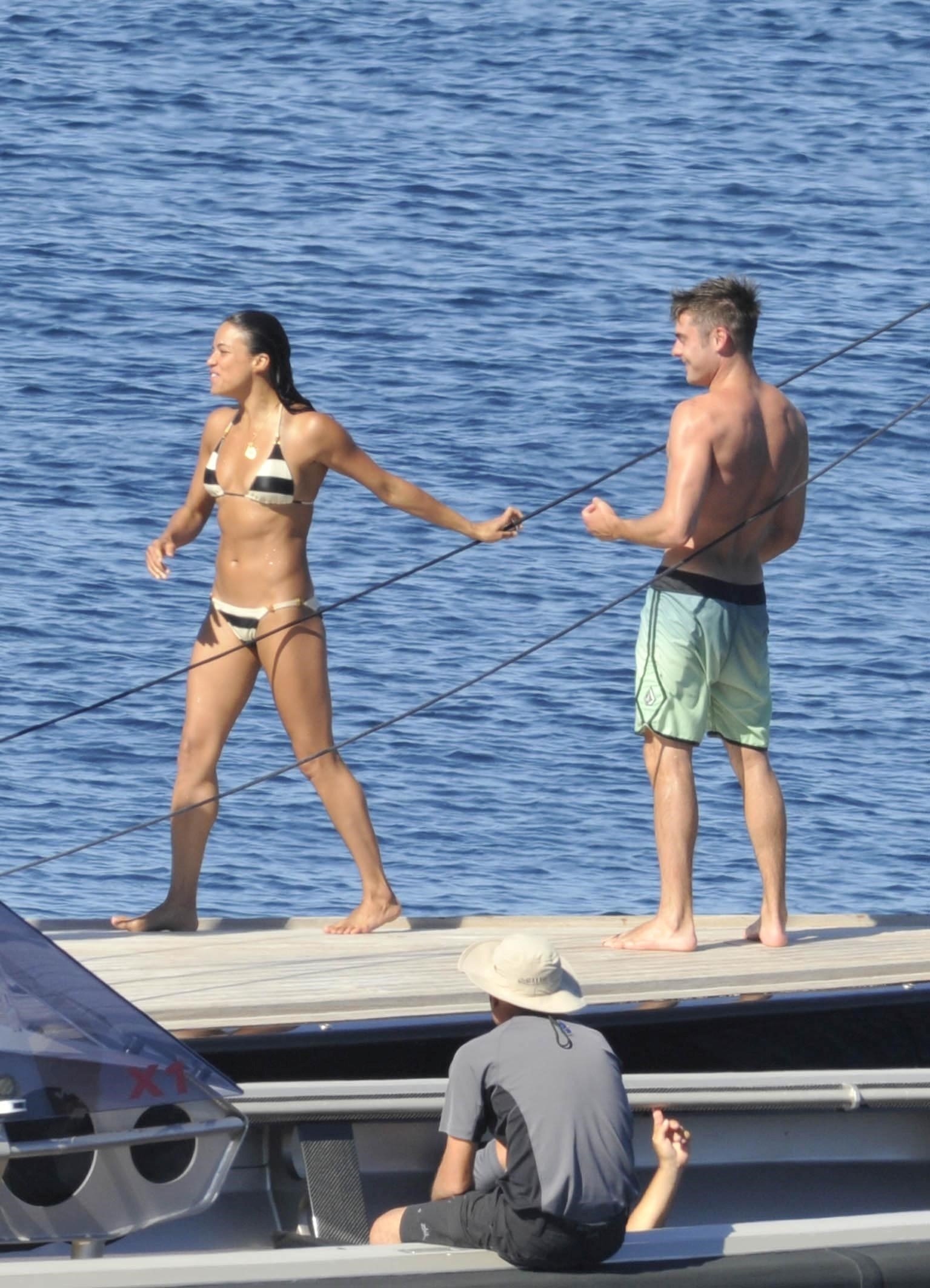 Michelle in a bikini and Zac in swim shorts by the water