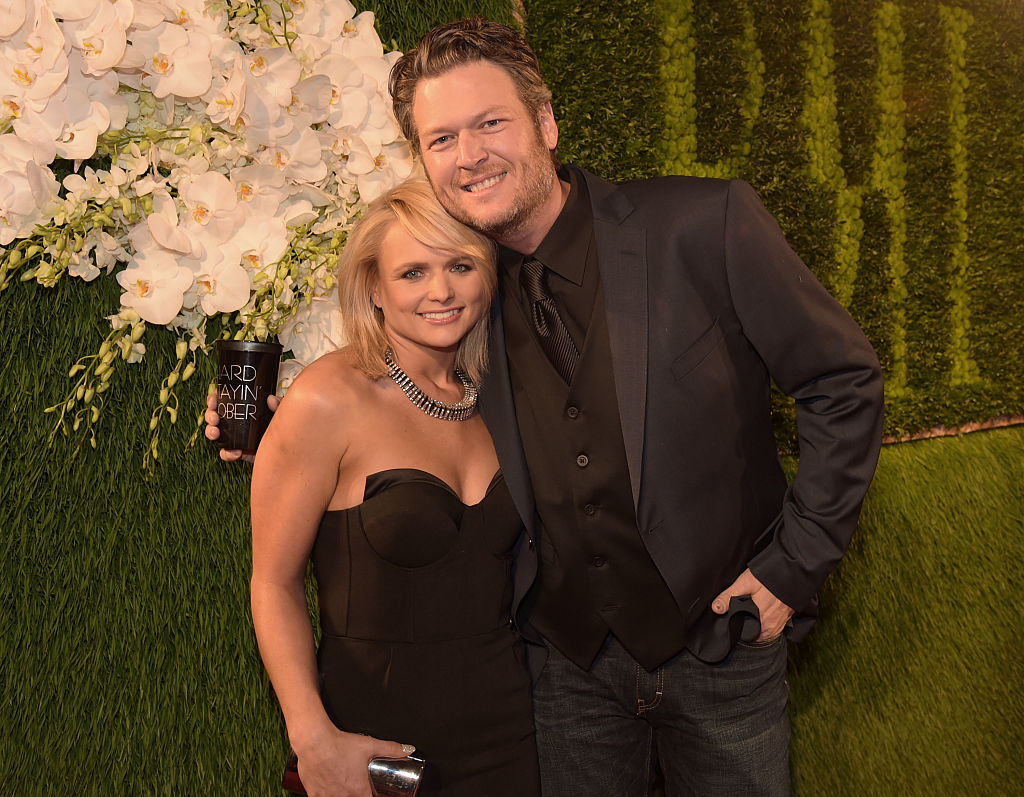 Miranda and Blake smiling, she in a strapless dress, he in a suit without a tie
