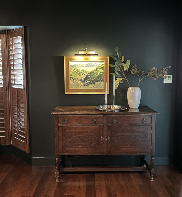 Elegant wooden sideboard with a framed landscape painting above it, accented by a modern lamp and decorative vase