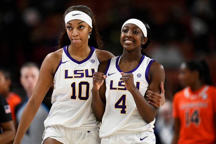 Two basketball players in LSU uniforms walking arm-in-arm on the court