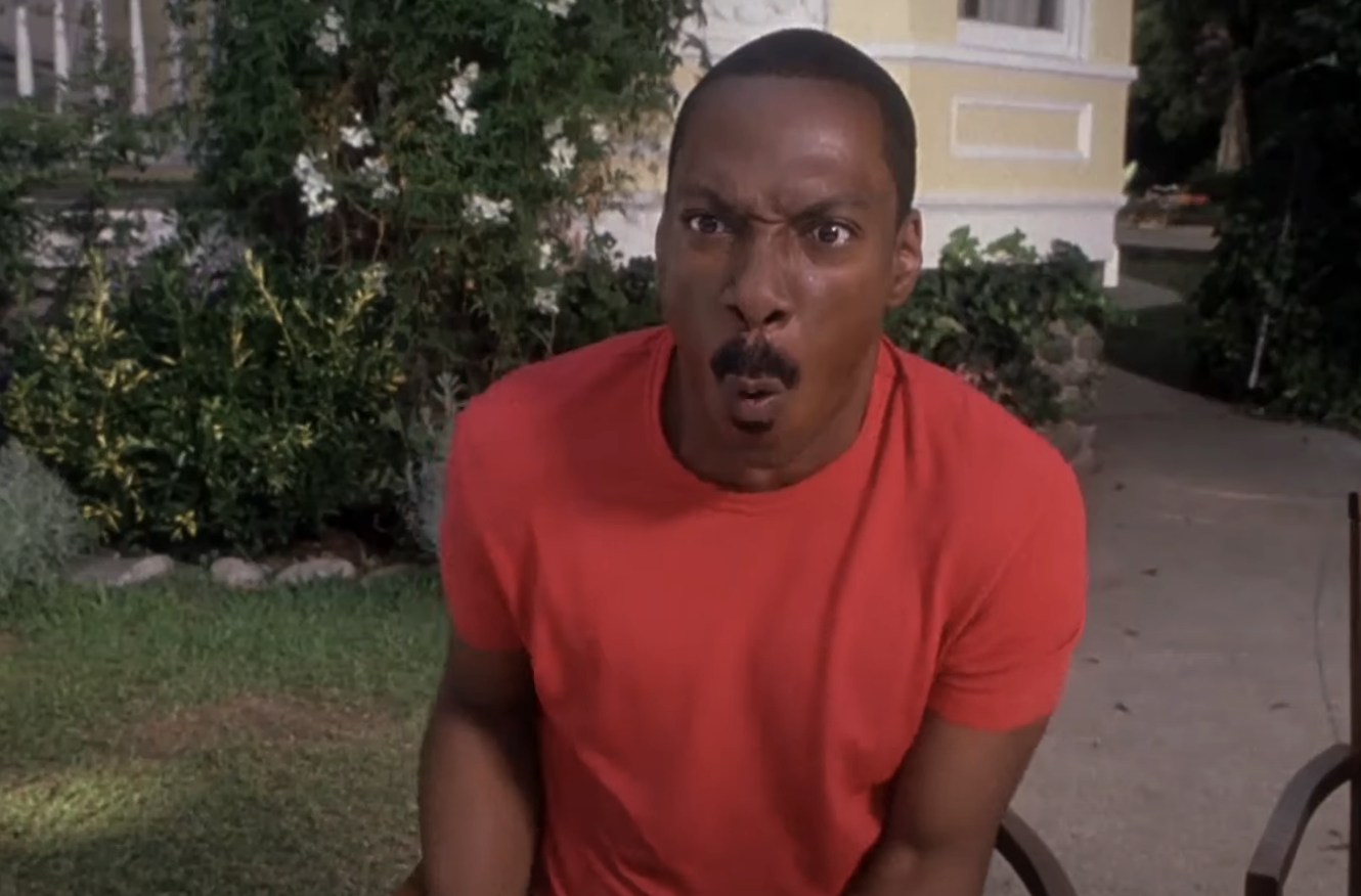 Eddie Murphy with an expression of surprise, wearing a red shirt, in a scene from a film