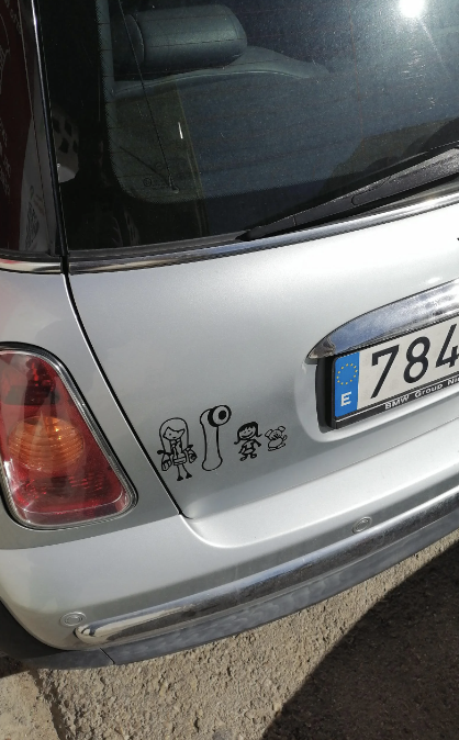 Family stick figure decal on a car, indicating a mom, vibrator, and one child, alongside a license plate