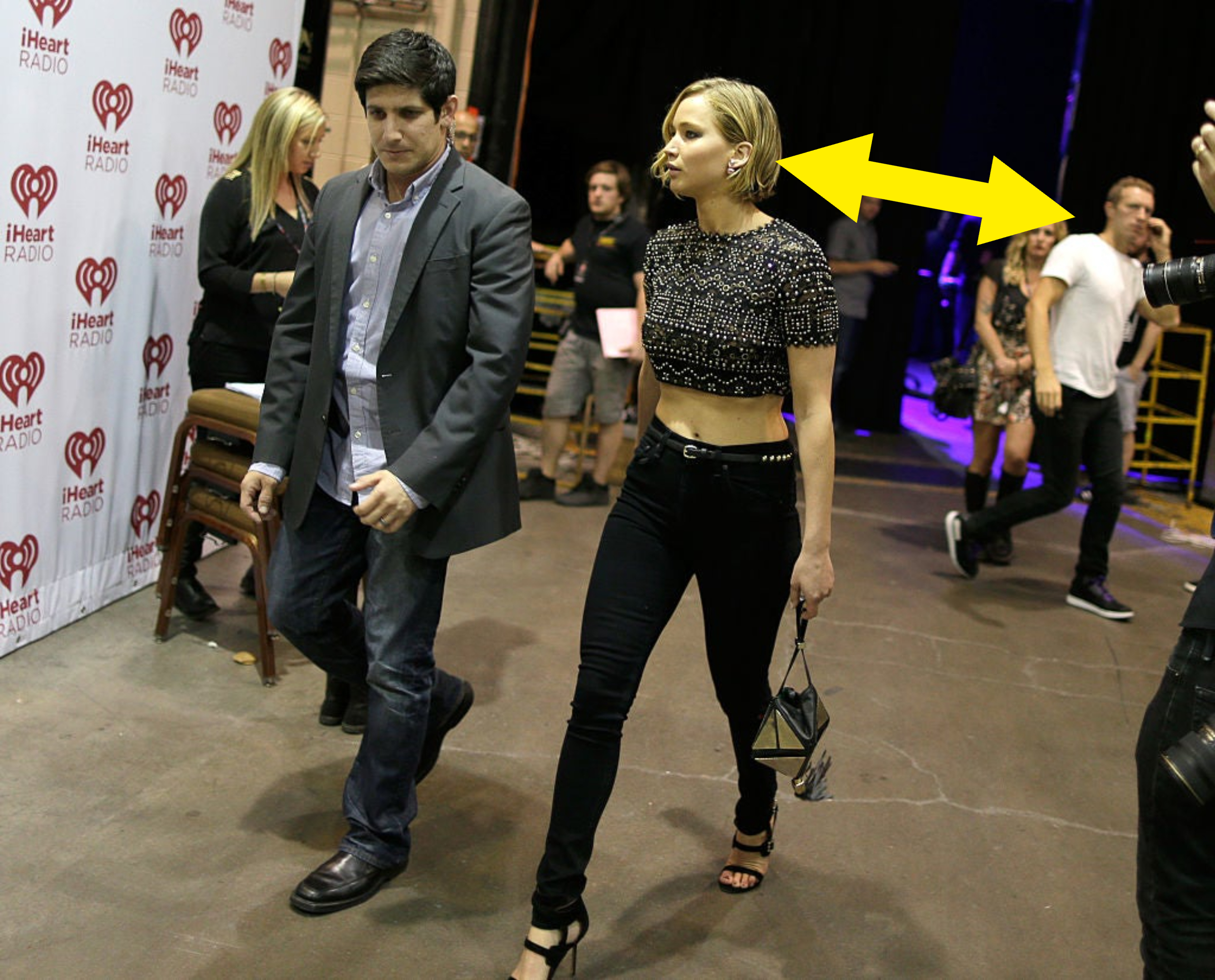 JLaw in cropped top and high-waisted pants and Chris in a T-shirt and jeans behind her walking the other way