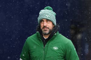 Man in a New York Jets beanie and green jacket standing in the snow