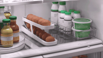 Refrigerator interior with an egg tray, bottled drinks, and food containers, demonstrating fridge organization for shopping
