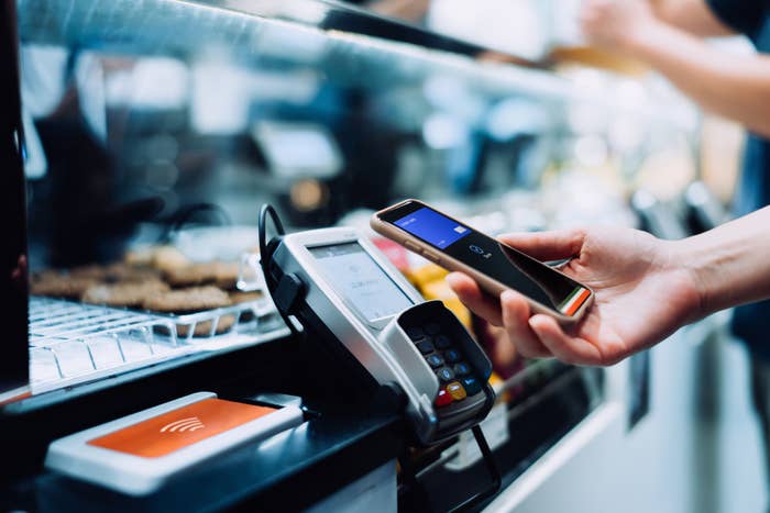 Person using smartphone to make a contactless payment at a store's POS terminal
