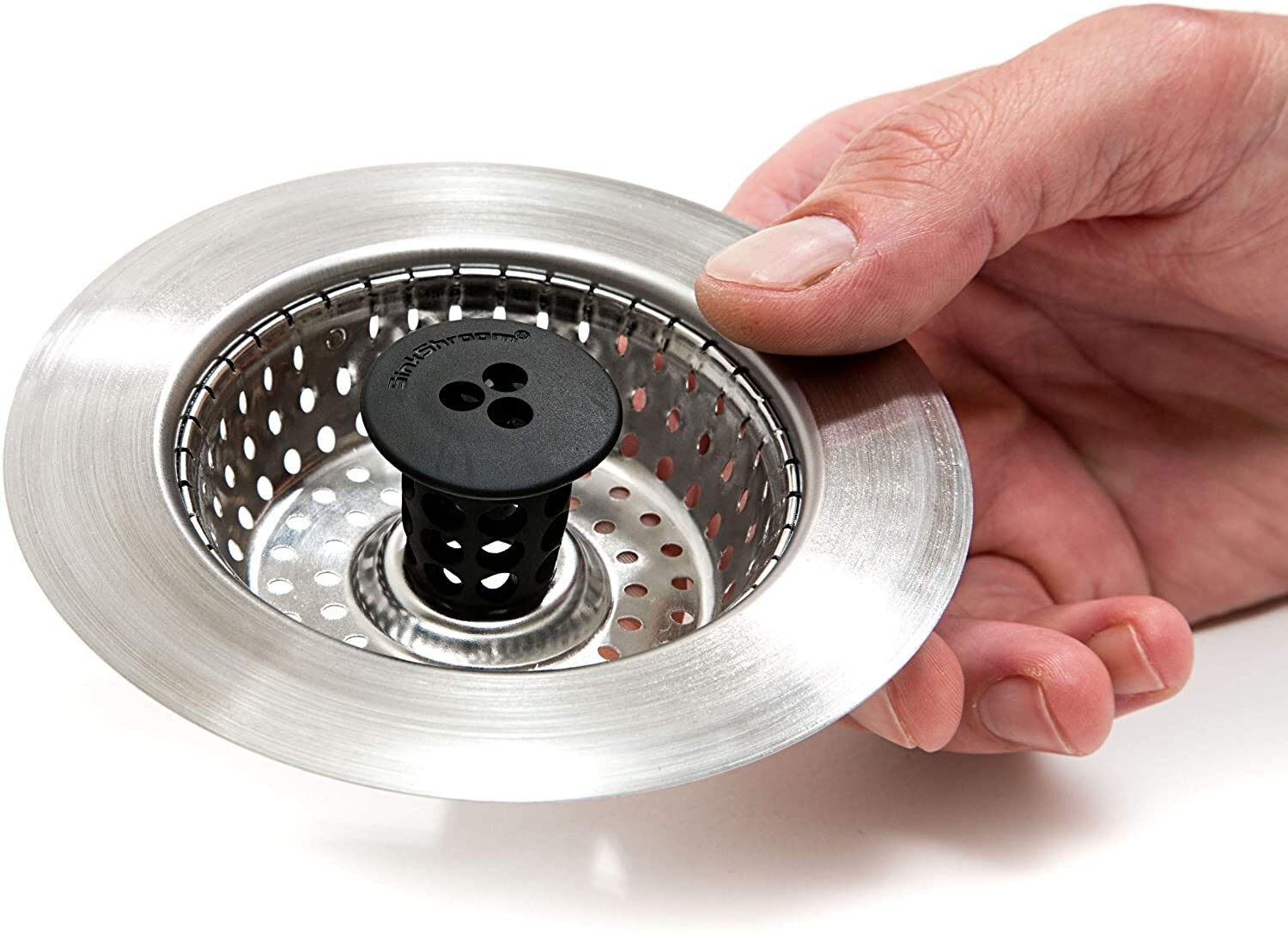 Hand placing a mesh kitchen sink strainer into the sink&#x27;s drain