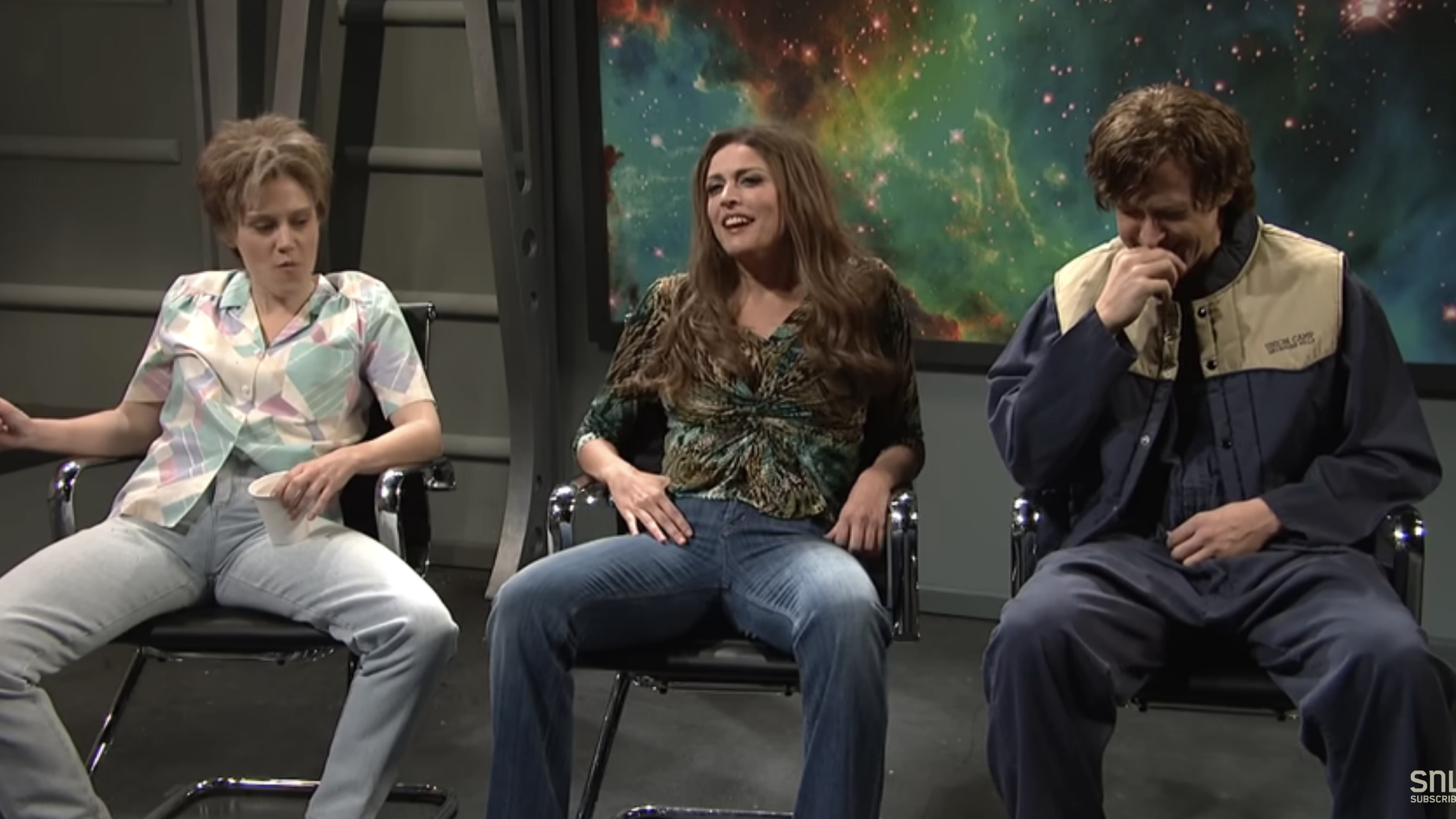 Three actors in a SNL sketch, sitting with a space backdrop