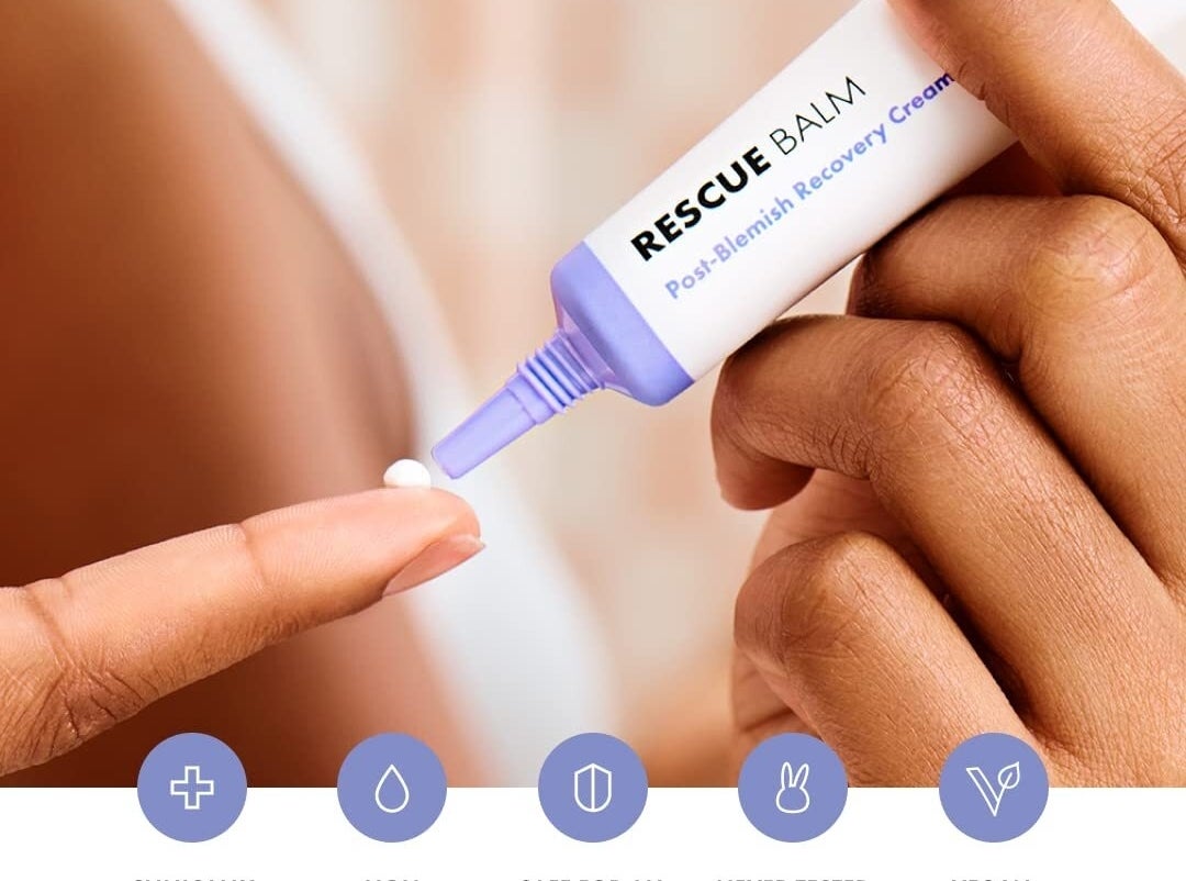 Hand applying Rescue Balm from a tube onto skin