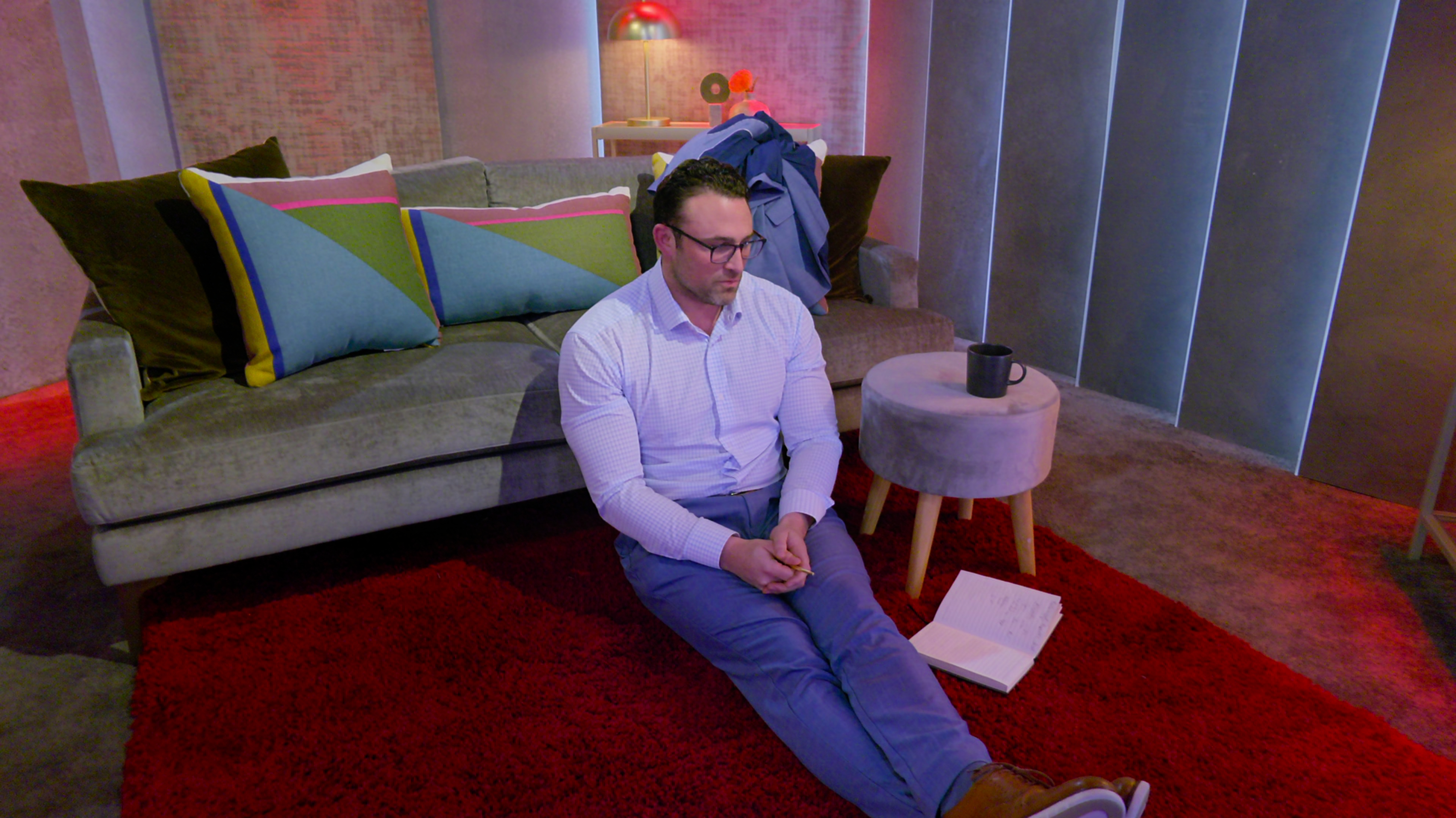 Matthew in glasses and casual attire sitting on floor in the pods