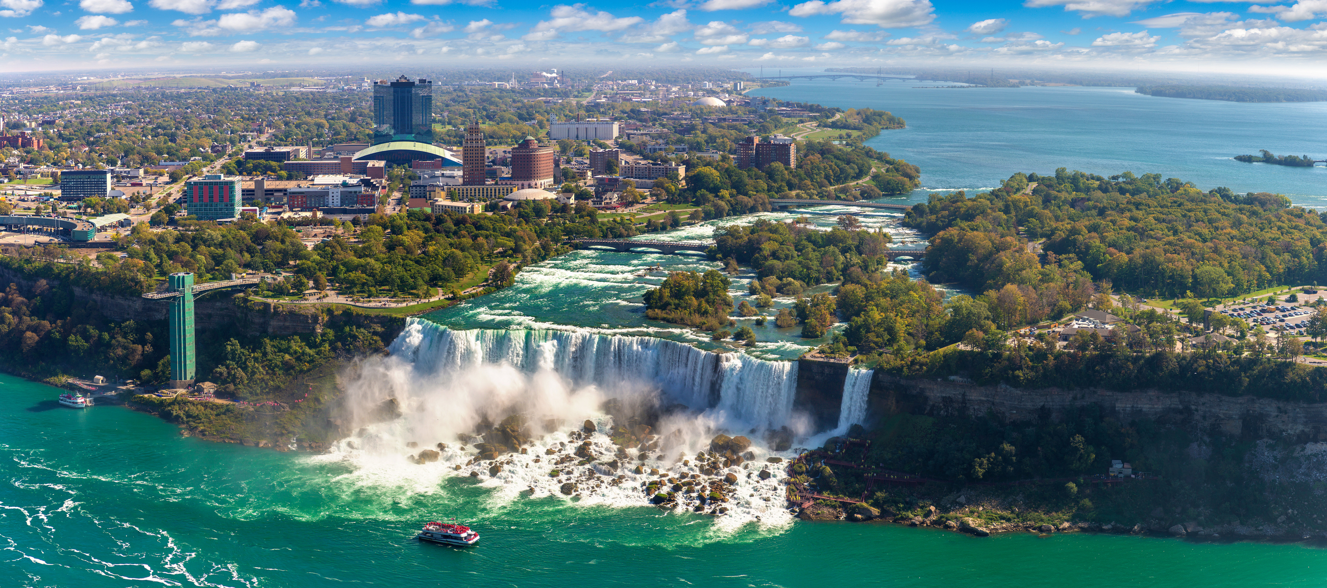 Aerial view of Niagara Falls with surrounding landscape and a boat near the mist