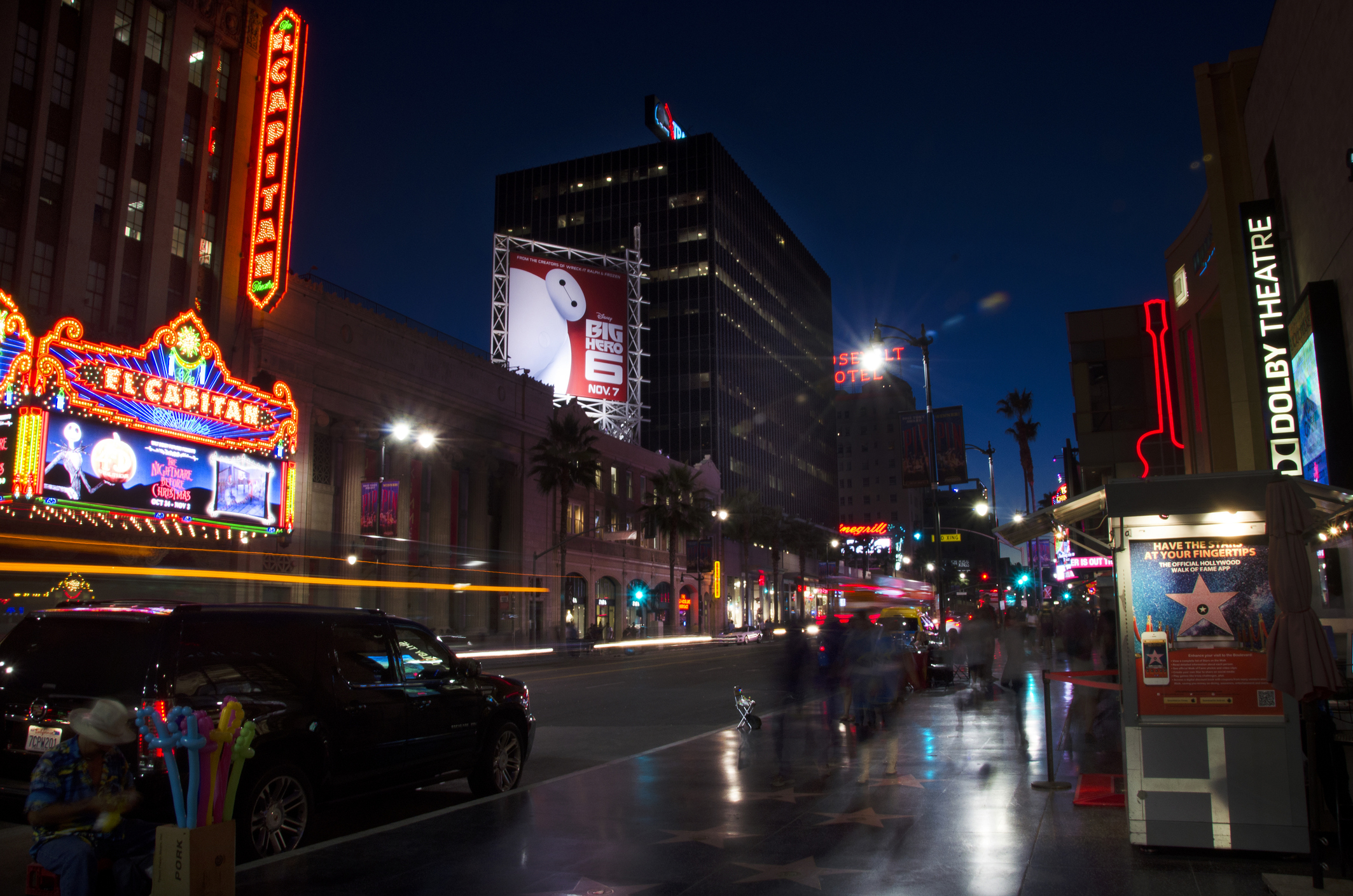 A Hollywood street at night with flashing signs and people