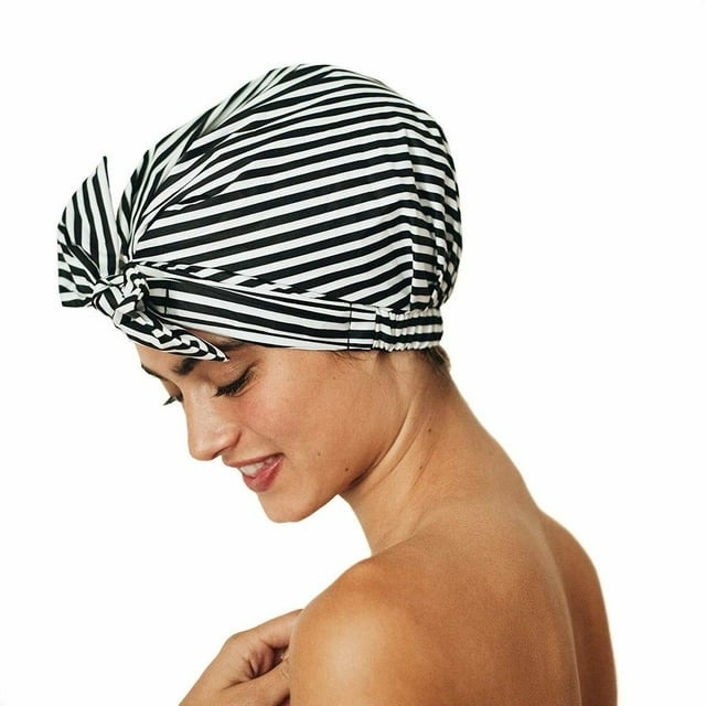 model smiling wearing a striped black and white shower cap
