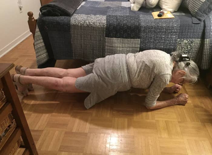 Older woman demonstrating a plank exercise on a wooden floor indoors