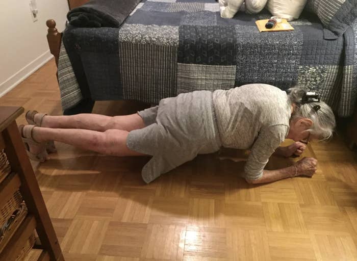 Elderly woman demonstrating a plank exercise on a wooden floor indoors