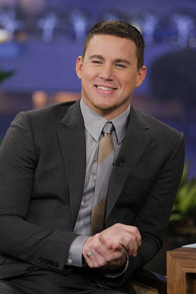 Channing in suit with tie sitting and smiling on a talk show set