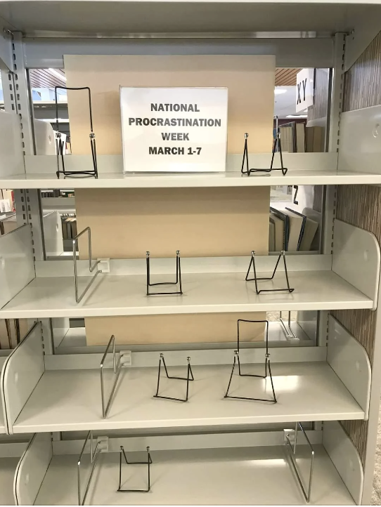 Sign on empty bookstore shelf reads &quot;National Procrastination Week March 1-7&quot;