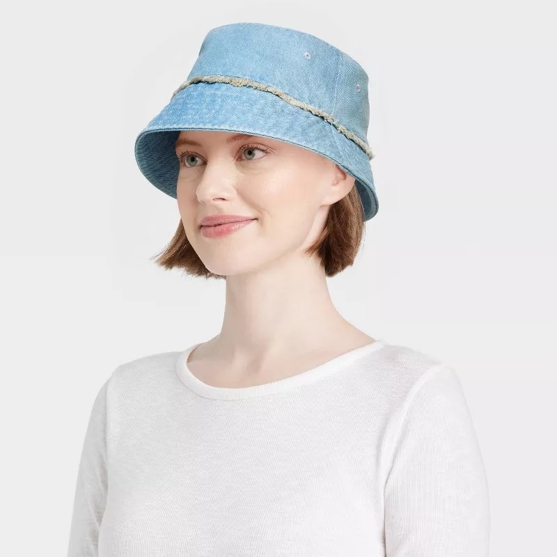 Model wearing a denim bucket hat with fringe around the middle